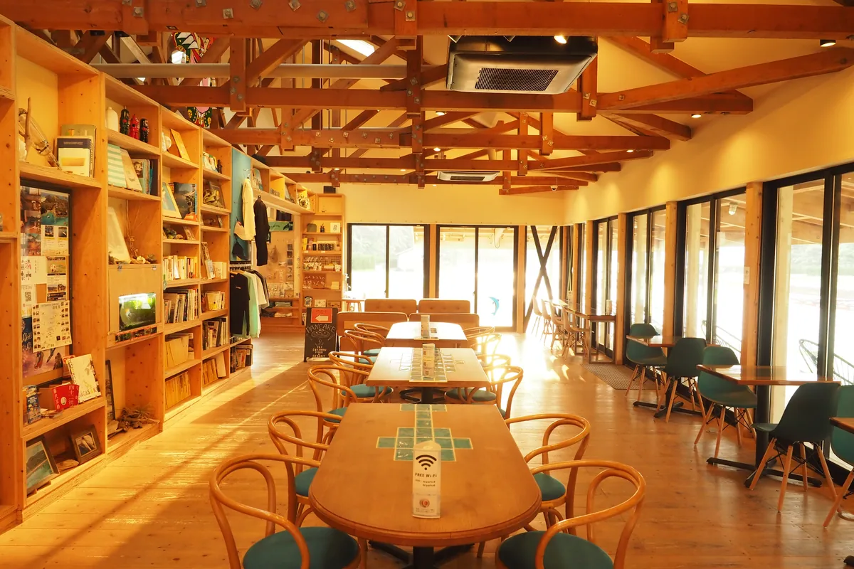 カフェの店内。長机と本棚が並び、大きな窓から園内が見える
