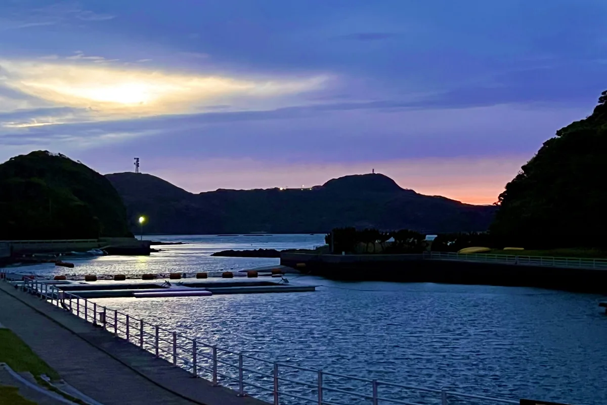 夕焼けに染まる入り江と海上デッキ