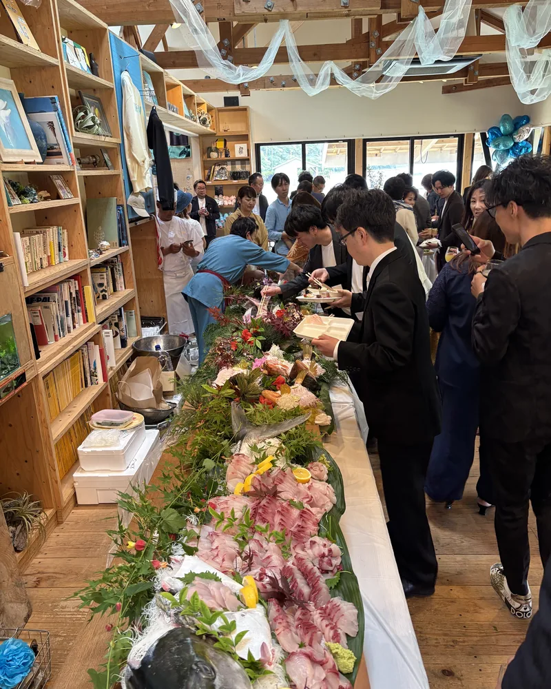 本棚の前に料理を並べたビュッフェの列に並ぶゲスト
